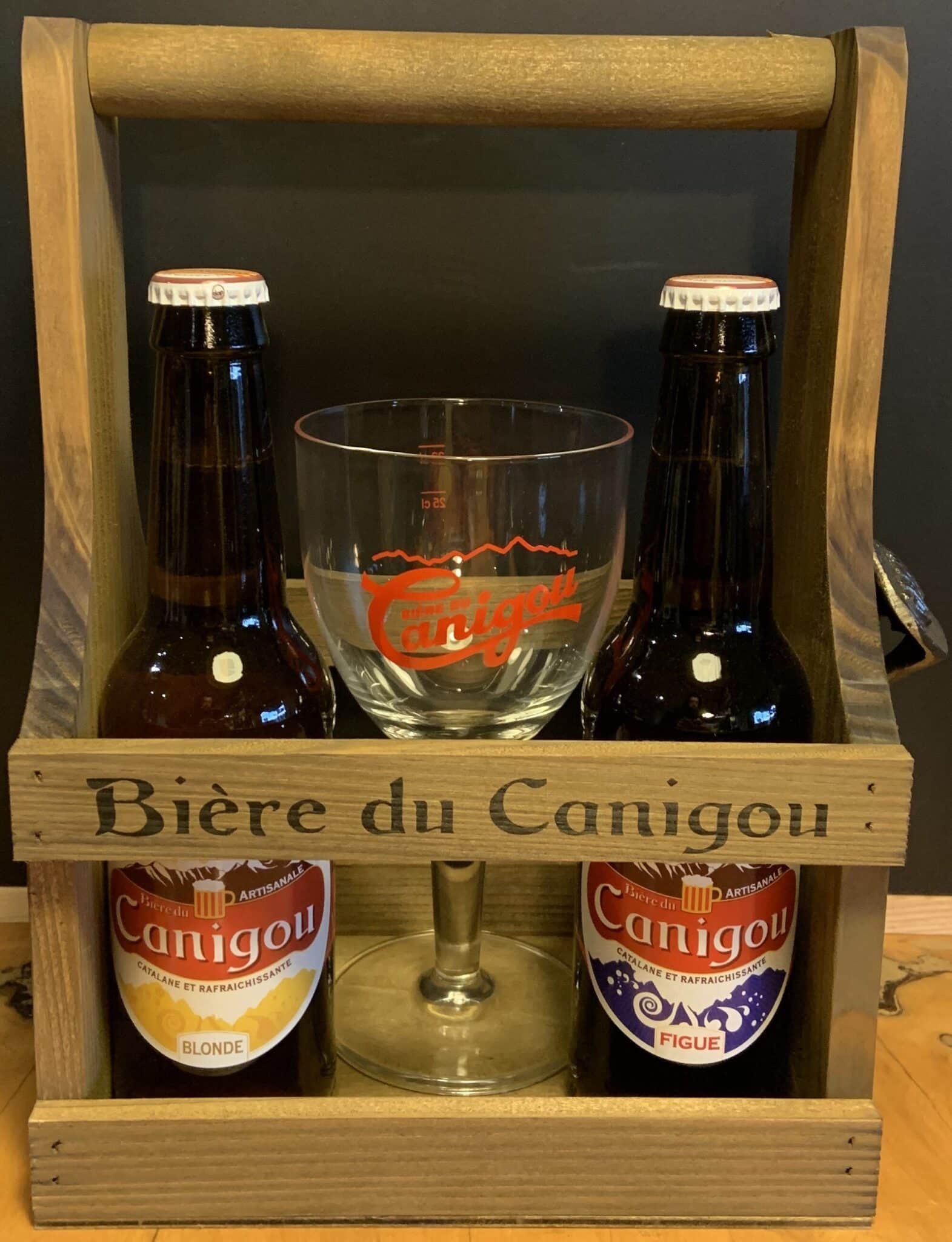 Un caddy en bois accueille deux bières Canigou : Blonde et Figue, avec un verre pour la dégustation.