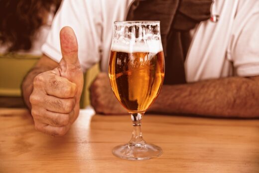 Personne avec un pouce levé près d'une bière artisanale.